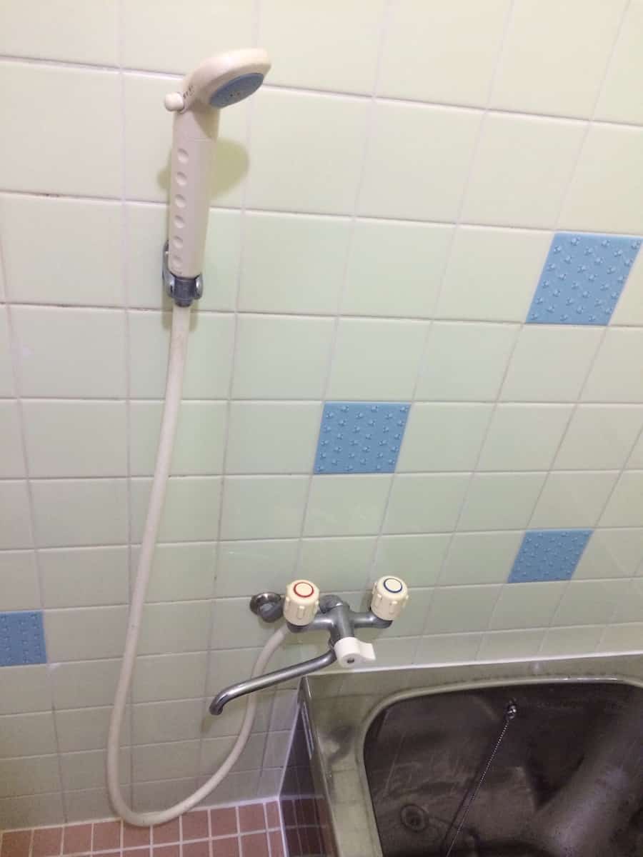自分で交換する前の浴室の古いツーハンドルタイプのシャワー混合栓