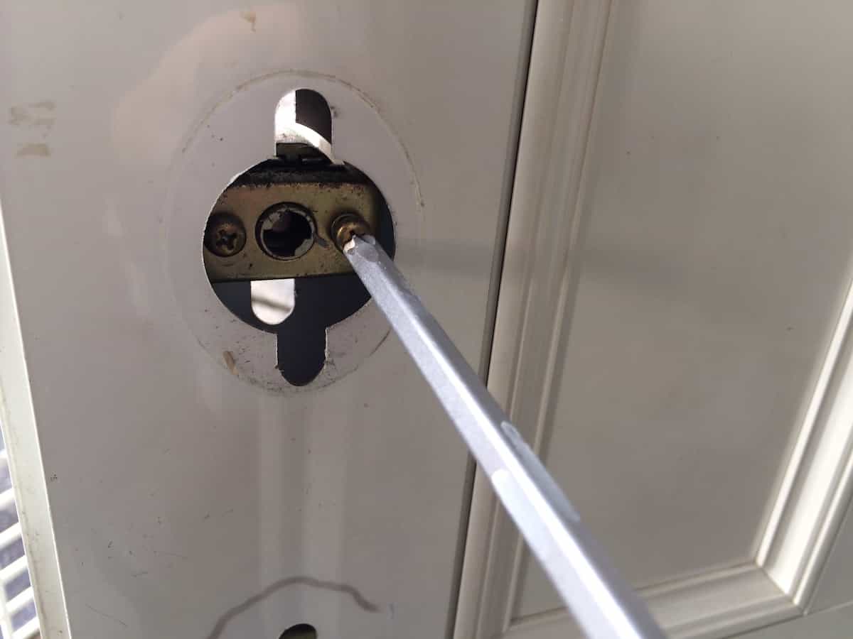 玄関扉の鍵シリンダーのネジを取り外す様子
