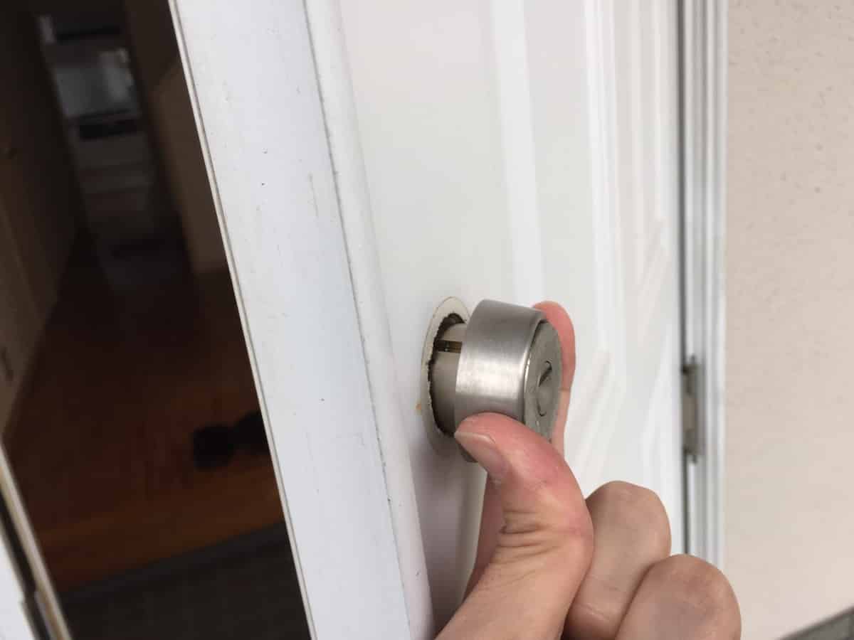 玄関扉の補助錠の鍵シリンダーを取り外す様子